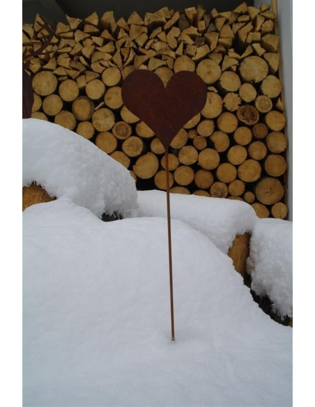Herz Gartenstecker als Winterdeko im Schnee vor einem Holzstapel